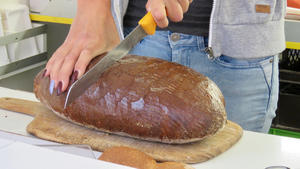Ein Laib Brot wird mit einem Messer in zwei Hlften geschnitten.